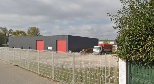 Le chemin du Grand Saint-Jean à Crest : un bâtiment en bardage gris à deux portes rouges, derrière une clôture grillagée.